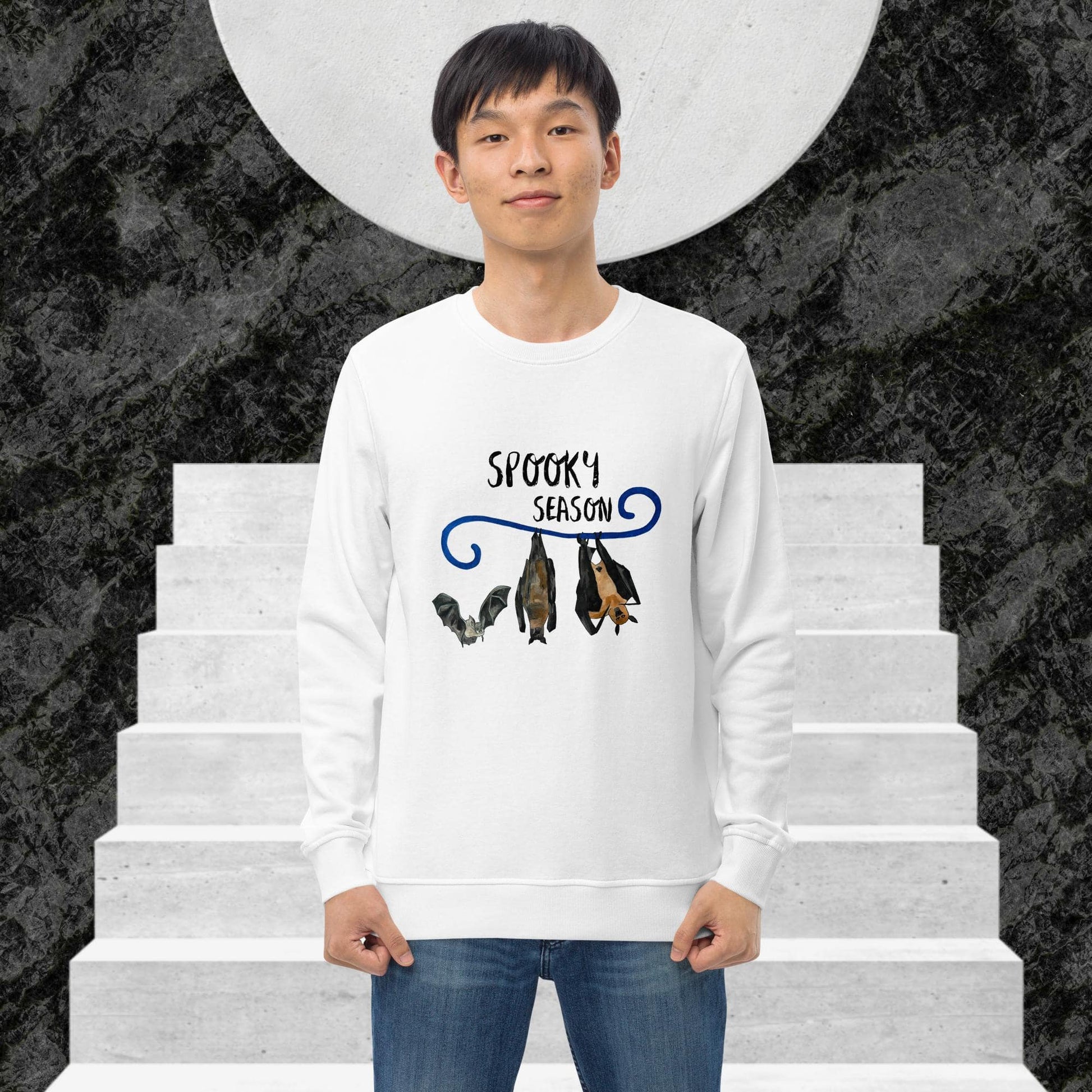 Man wearing a white sweatshirt with 'Spooky Season' design on a staircase background