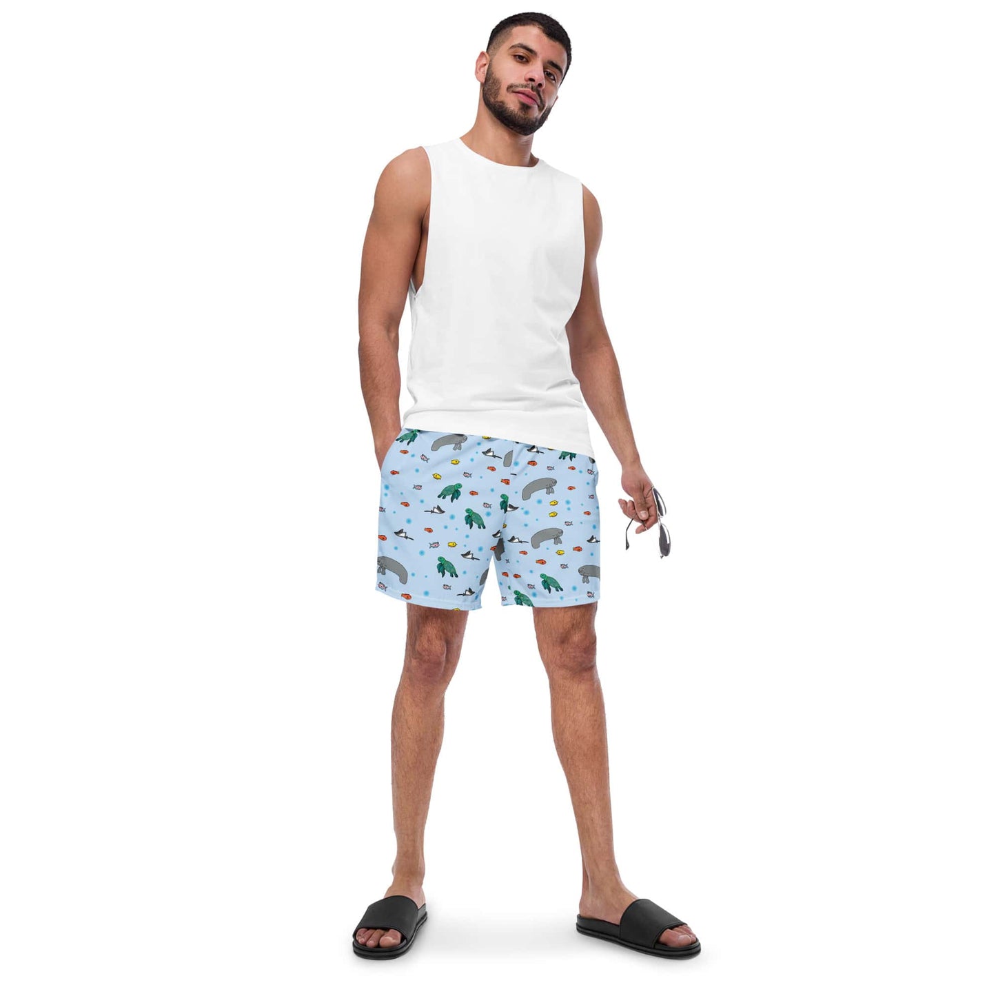 Model wearing men’s swim trunks with a turtle and manatee design, paired with a shirt.