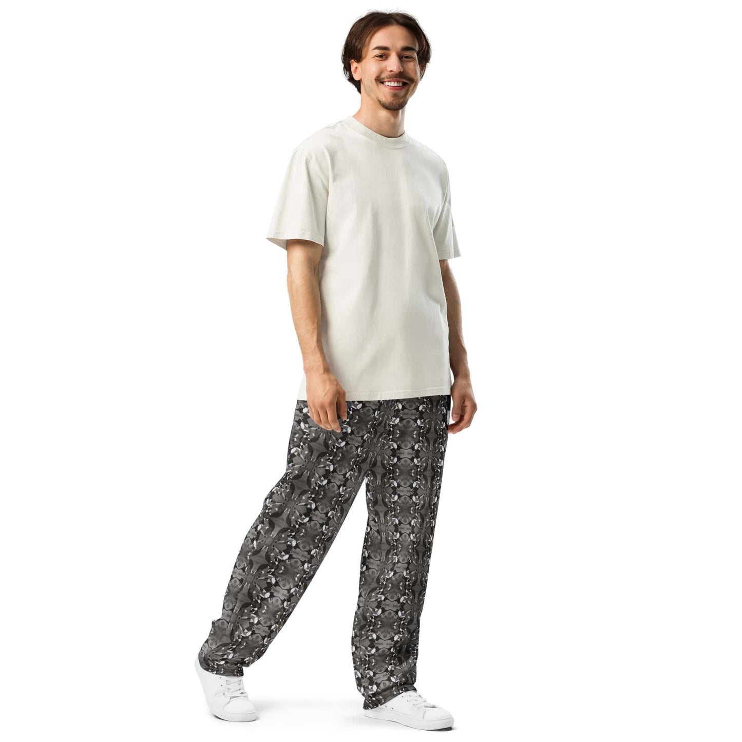 A model in a three-quarter front-left pose, highlighting the wide-leg cut and intricate bird pattern of the joggers.