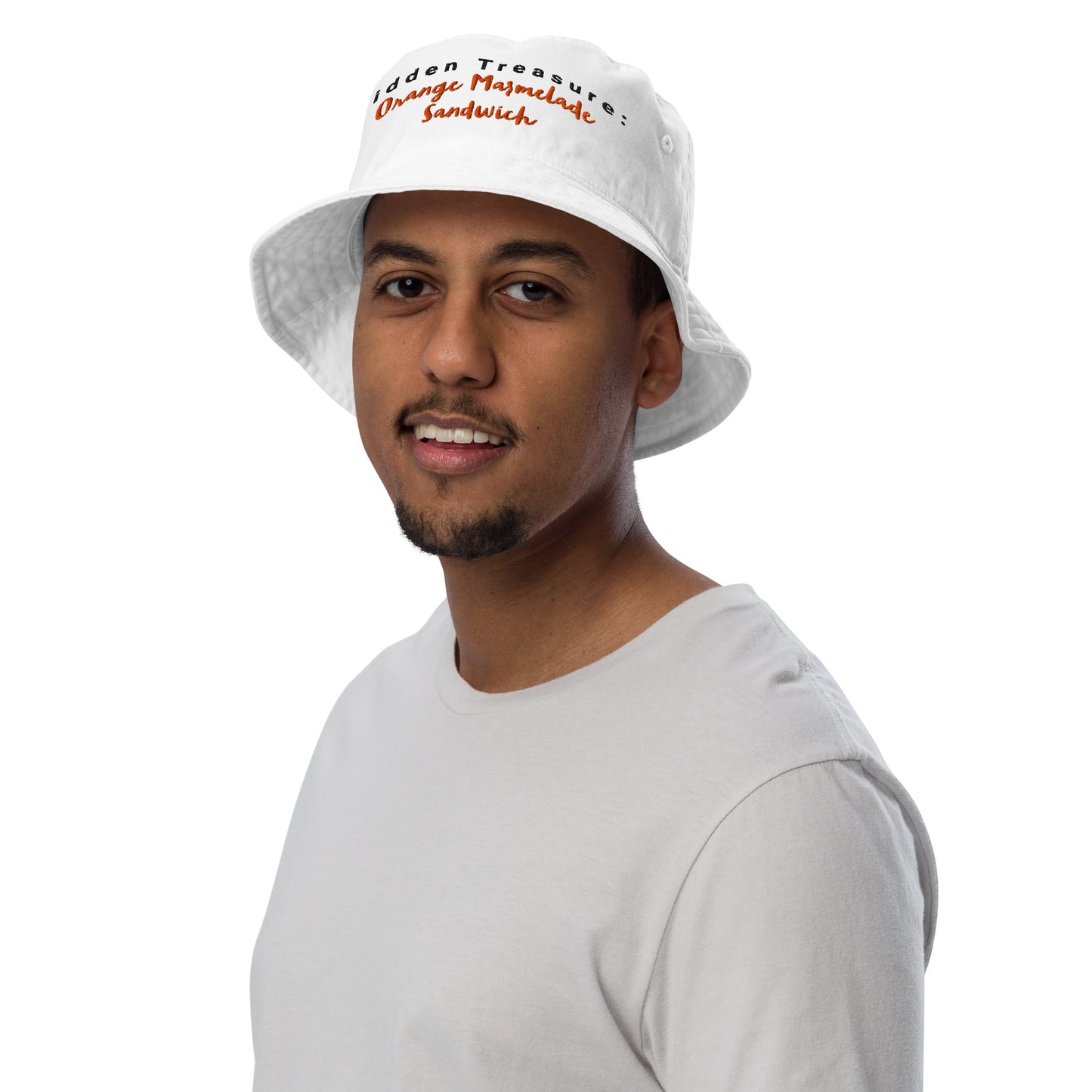 Model wearing a white bucket hat with "Hidden Treasure: Orange Marmalade Sandwich" embroidery on the front, adding a playful touch to their outfit.