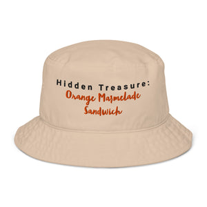 Beige embroidered bucket hat with the phrase "Hidden Treasure: Orange Marmalade Sandwich" stitched in black and orange on the front.