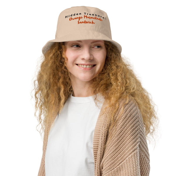 Model wearing a beige bucket hat with "Hidden Treasure: Orange Marmalade Sandwich" embroidery on the front, adding a playful touch to their outfit.