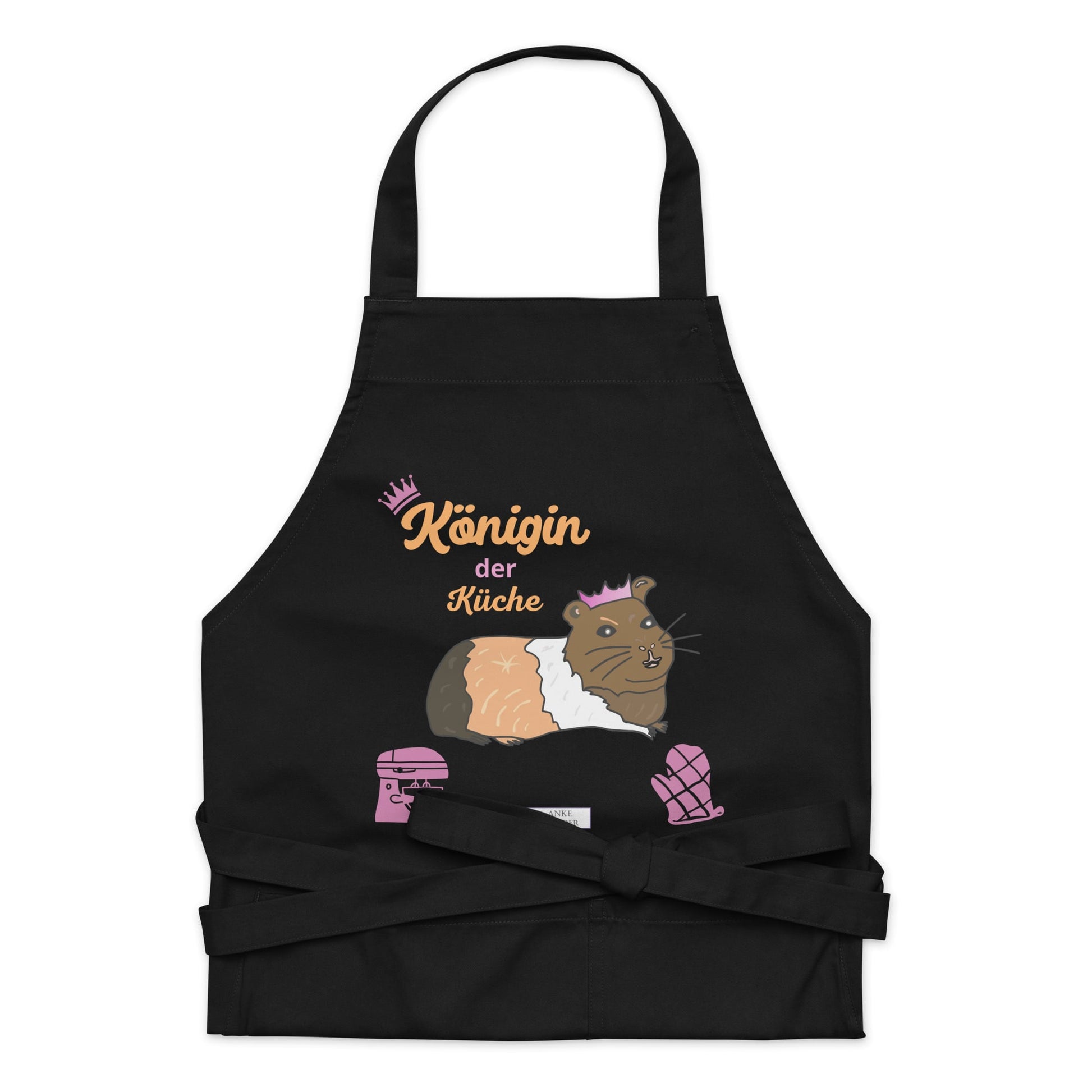 A flat-lay image of the black apron highlighting the detailed guinea pig illustration and the “Königin der Küche” lettering.