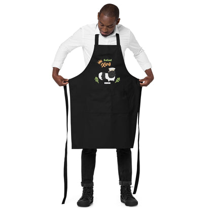 A man wears a black Salad King apron, showcasing a cute guinea pig with a chef’s hat and adjustable straps