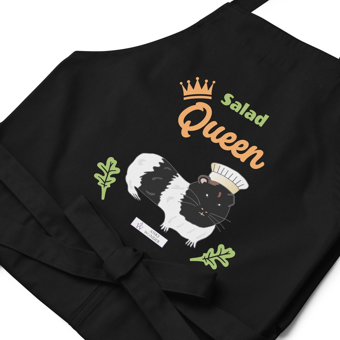 A detailed flat-lay of the black apron, highlighting the adorable guinea pig chef design and the Anke Wonder logo.