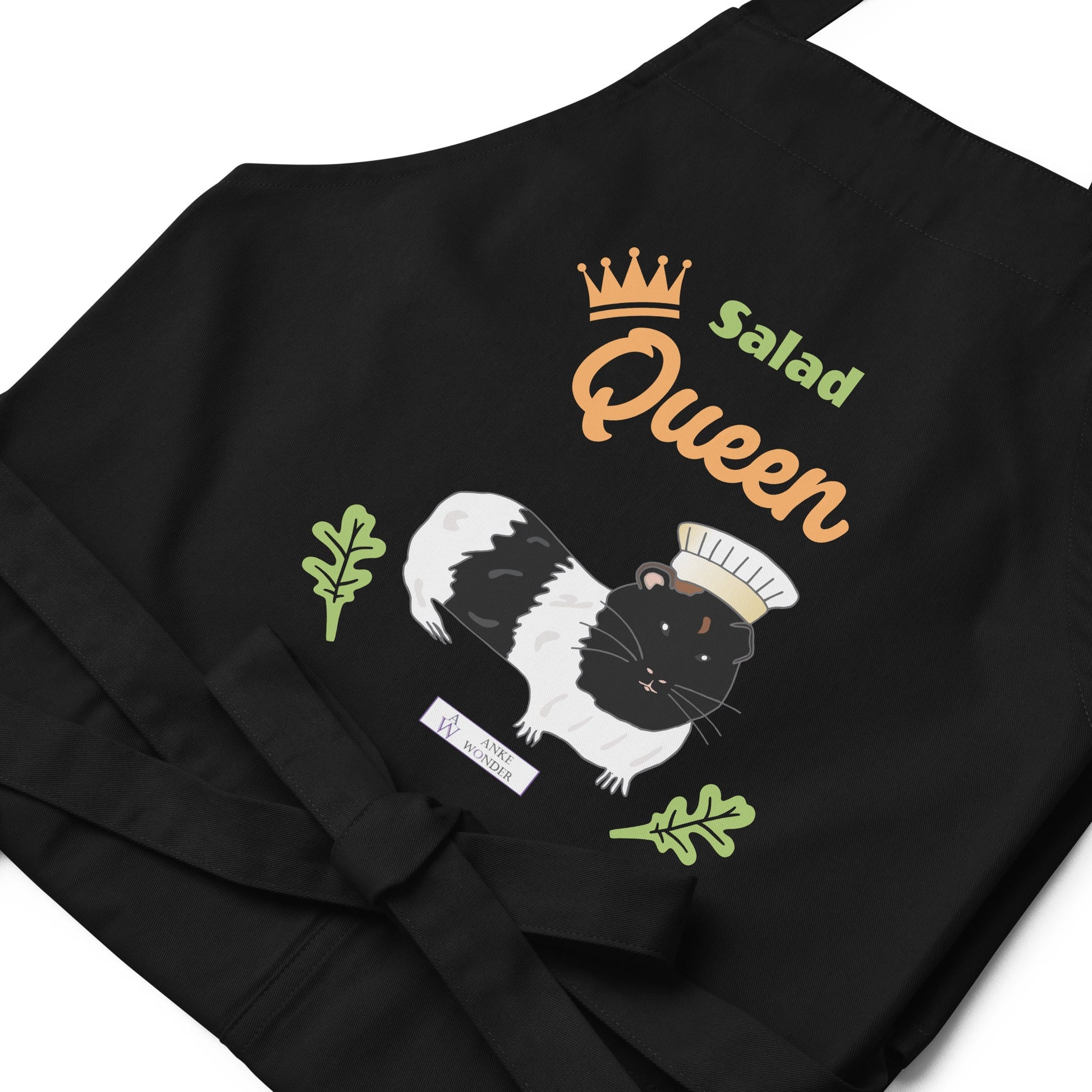 A detailed flat-lay of the black apron, highlighting the adorable guinea pig chef design and the Anke Wonder logo.