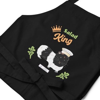 A flat-lay of the black Salad King apron, showing the detailed guinea pig illustration and the Anke Wonder Logo.