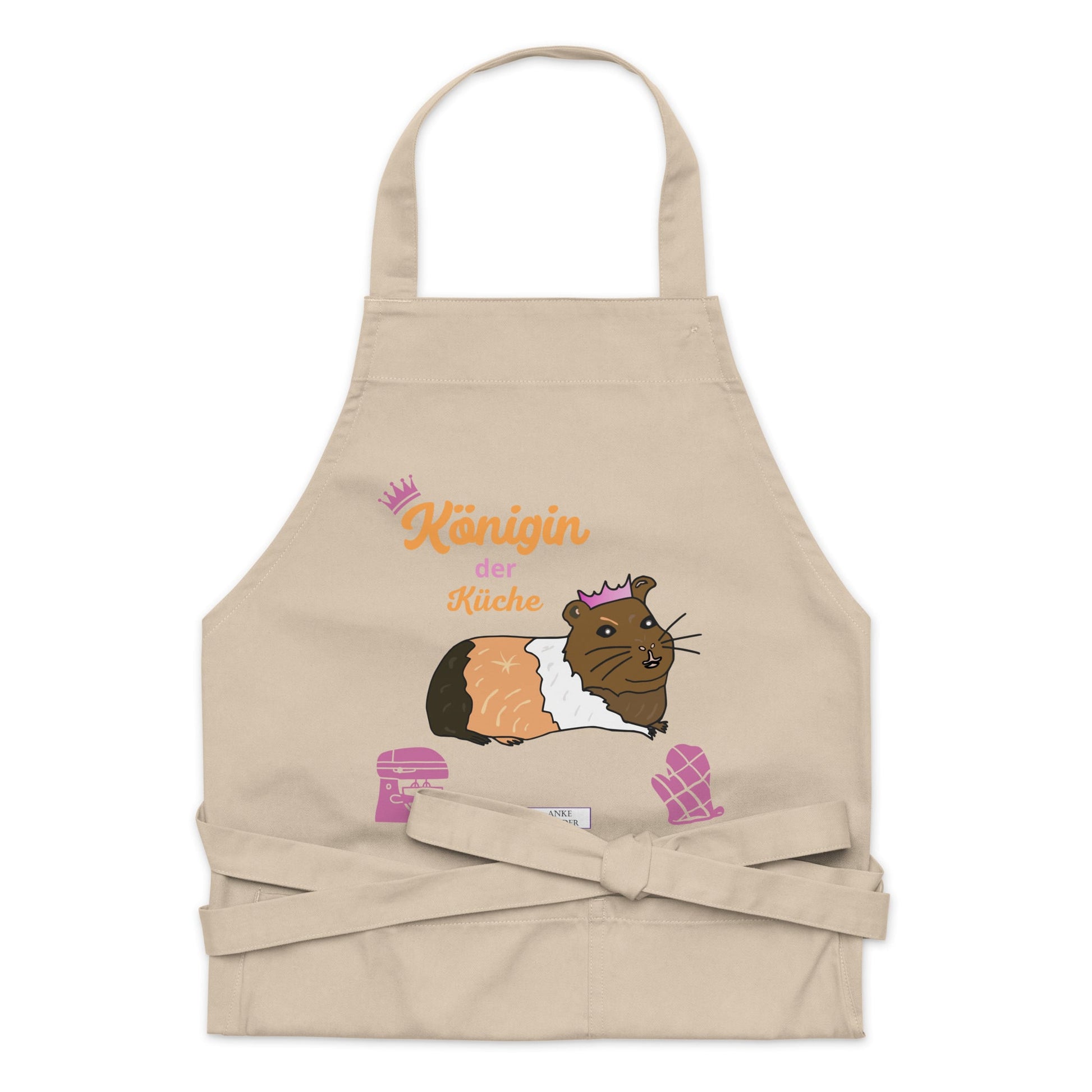 A flat-lay of the natural apron displaying the detailed guinea pig design and “Königin der Küche” typography.