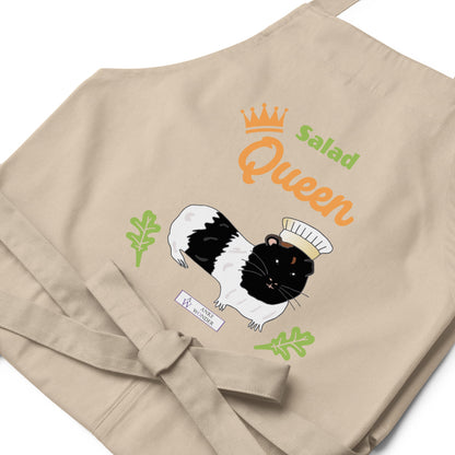 A flat-lay of the beige Salad Queen apron, showing the detailed guinea pig chef illustration and the Anke Wonder logo.