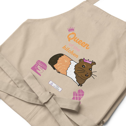 A flat-lay of the natural apron featuring the guinea pig in a pink crown and fun typography spelling “Queen of the Kitchen and the Anke Wonder branding.