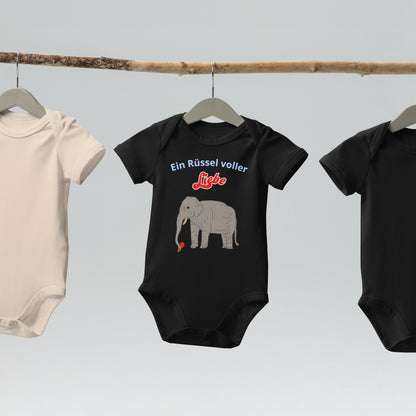  “Ein Rüssel voller Liebe” baby bodysuits with elephant design in black hanging on wooden hangers.