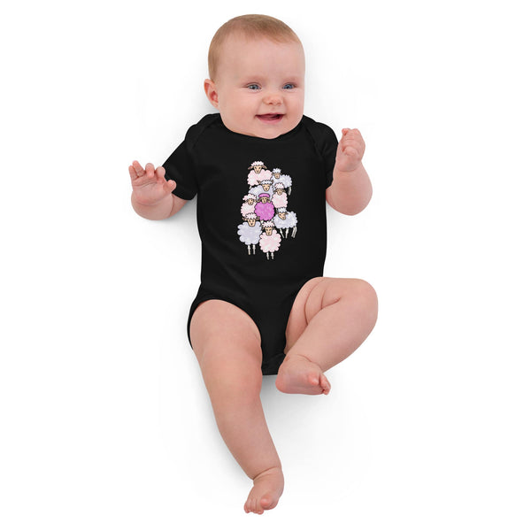 Baby girl lying down in a black soft organic cotton pink sheep bodysuit, designed by Anke Wonder.