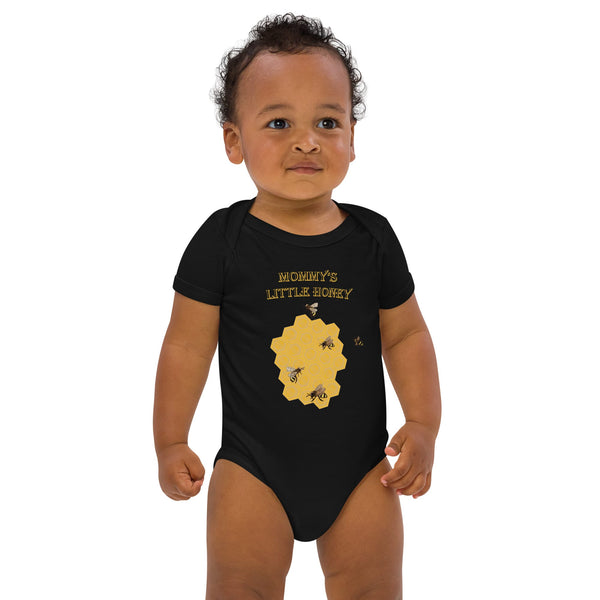 Young boy wearing a black organic baby bodysuit with a honeybee design, smiling at the camera.