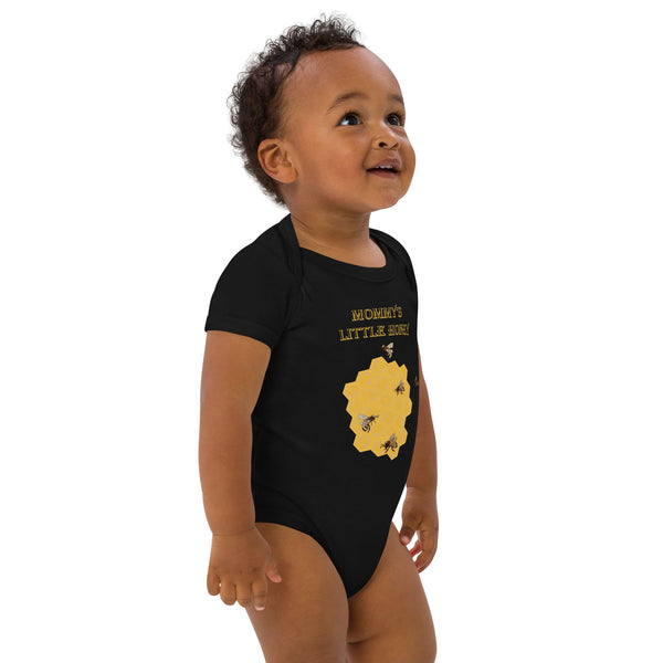 Toddler boy standing slightly to the right, showcasing the front of a black organic cotton bodysuit with a bee and honeycomb print.