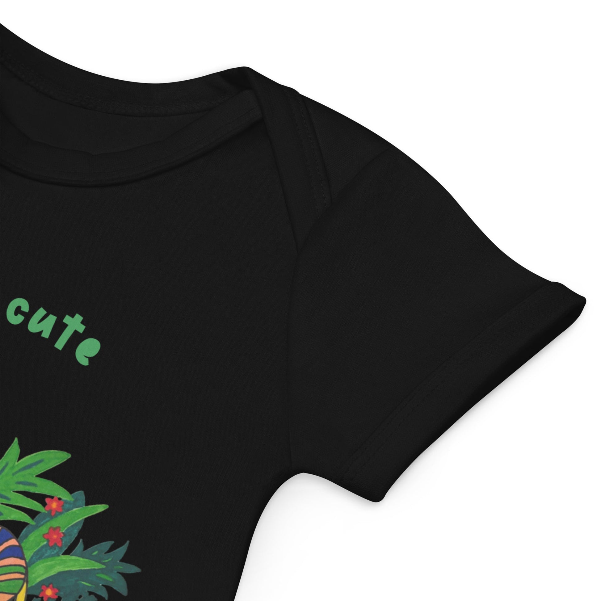 Sleeve detail of black onesie with colorful design and 'cute' text on a white background