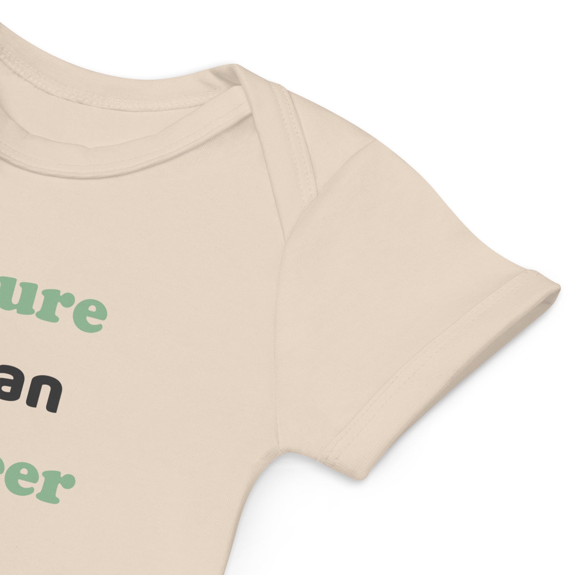 A close-up view of the sleeve of a natural-colored organic cotton baby bodysuit, displaying its raw, eco-friendly fabric and fine craftsmanship.
