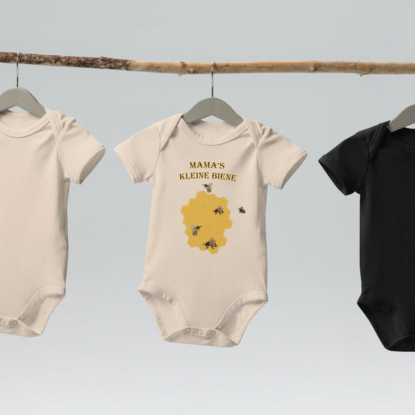 Natural organic cotton baby bodysuit with a honeycomb and bee design, featuring "Mama's Kleine Biene" text, displayed on a hanger.