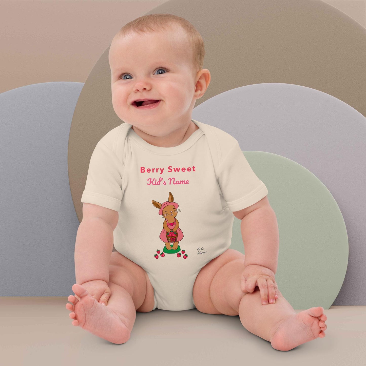 Baby Girl wearing a onesie with a printed bunny with strawberries design and text 'Berry Sweet Name', sitting on a colorful background