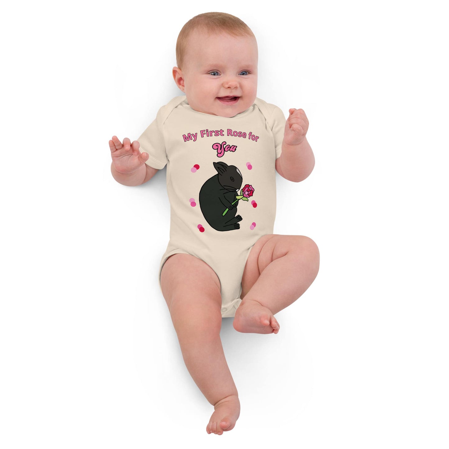 Smiling baby girl laying in a natural-colored baby bodysuit with a rabbit design and pink flower print.