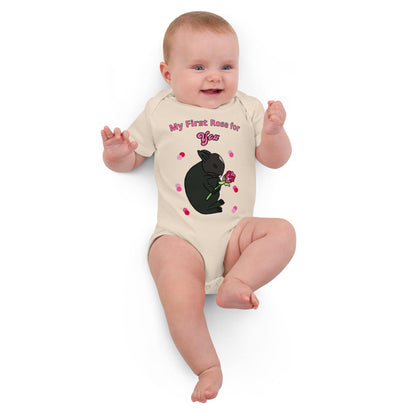 Smiling baby girl laying in a natural-colored baby bodysuit with a rabbit design and pink flower print.