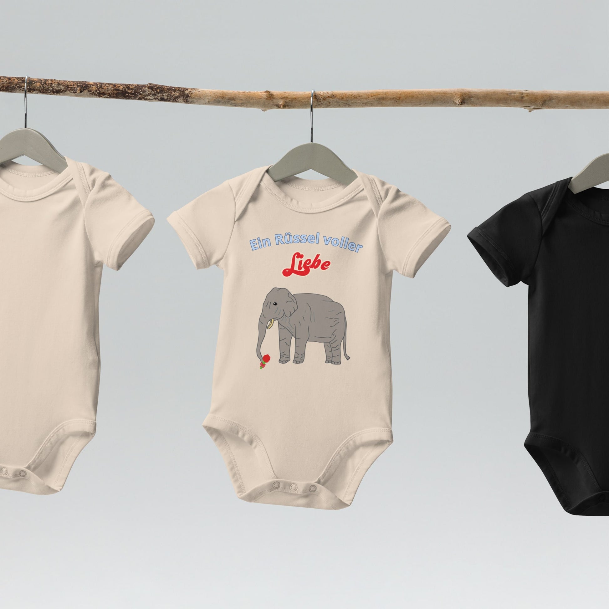  “Ein Rüssel voller Liebe” baby bodysuits with elephant design in organic natural hanging on wooden hangers.