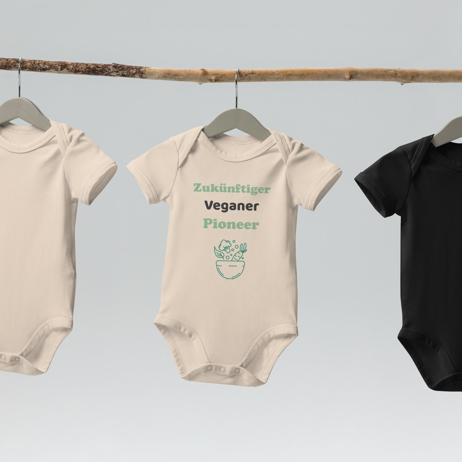 A natural-colored organic cotton baby bodysuit with 'Zuküftiger Veganer Pioneer' design hanging on a wooden hanger, highlighting its sustainable, unbleached fabric.