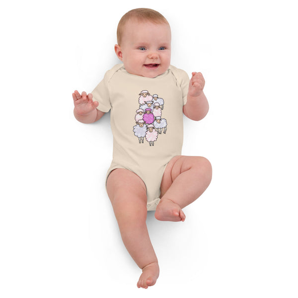 Baby girl lying down in a soft organic cotton pink sheep bodysuit, relaxed and cozy.