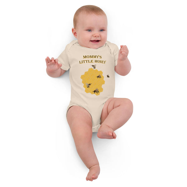 Infant girl lying down in a natural organic cotton bodysuit with a honeybee print, looking cozy and content.