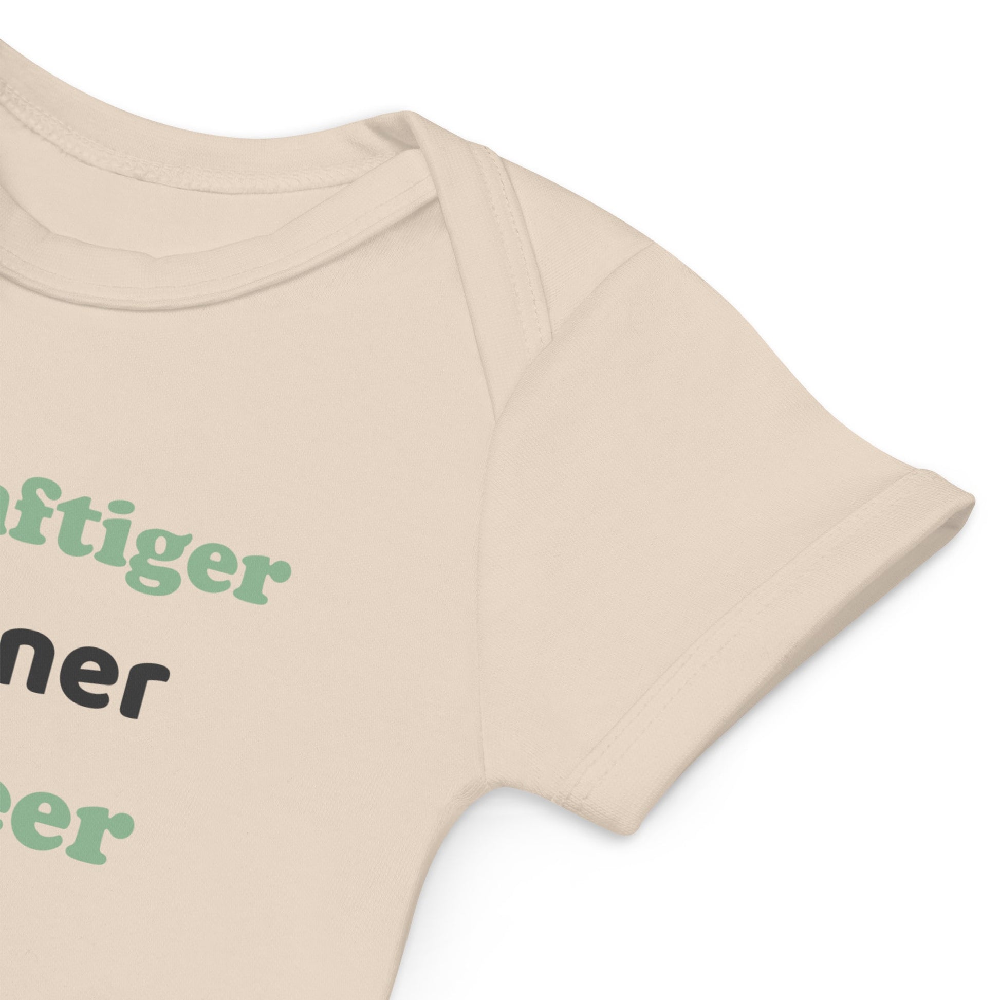  A close-up of the sleeve of a natural-colored organic cotton baby bodysuit with vegan design, displaying its eco-friendly fabric and fine craftsmanship.