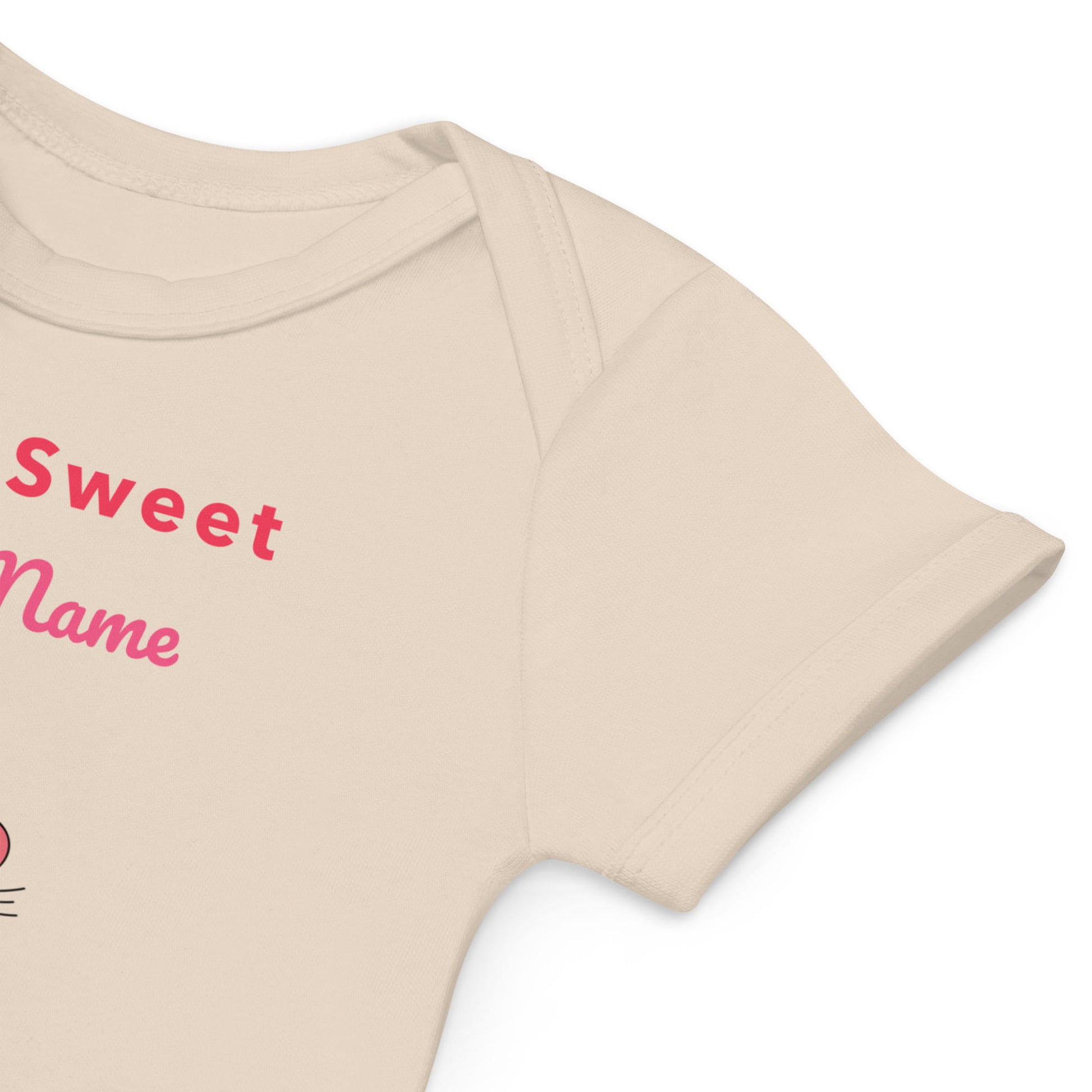 Sleeve of beige baby romper with pink text and on a white background