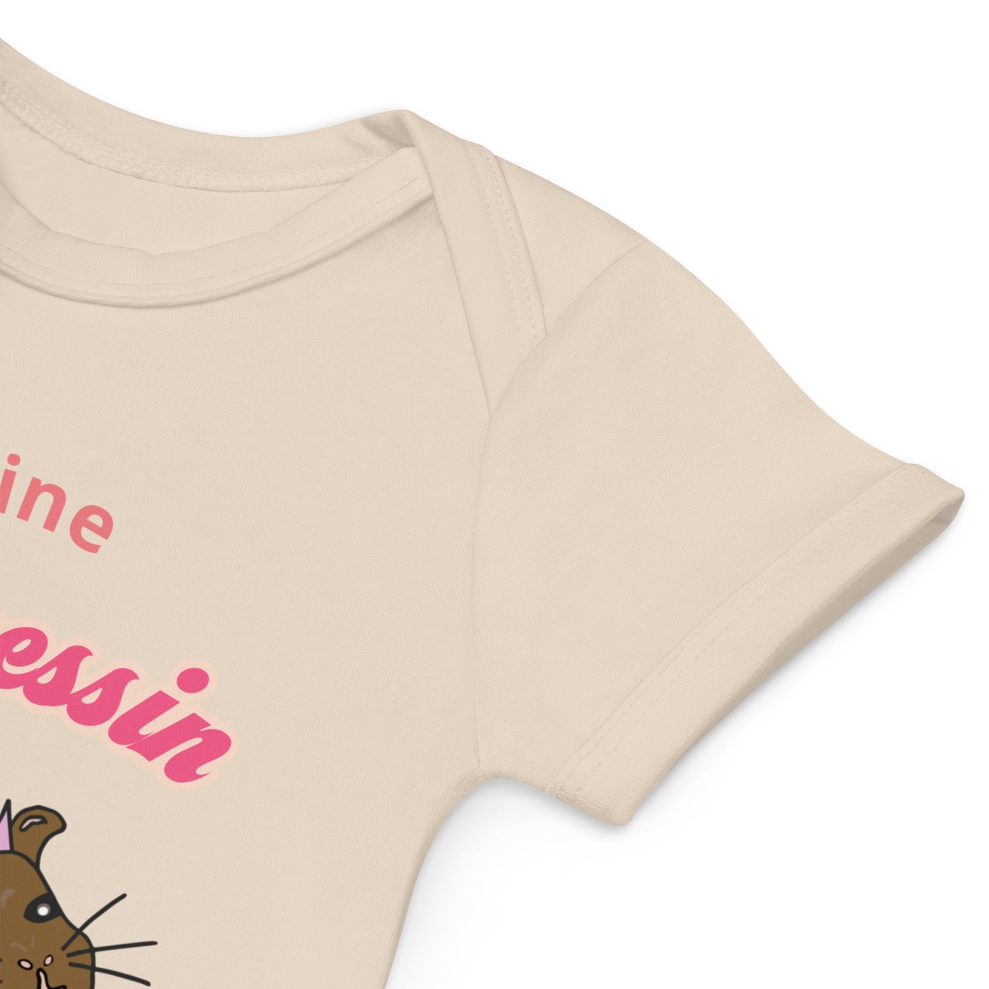 Natural-colored baby girl bodysuit sleeve close-up with guinea pig design, highlighting quality organic cotton material.