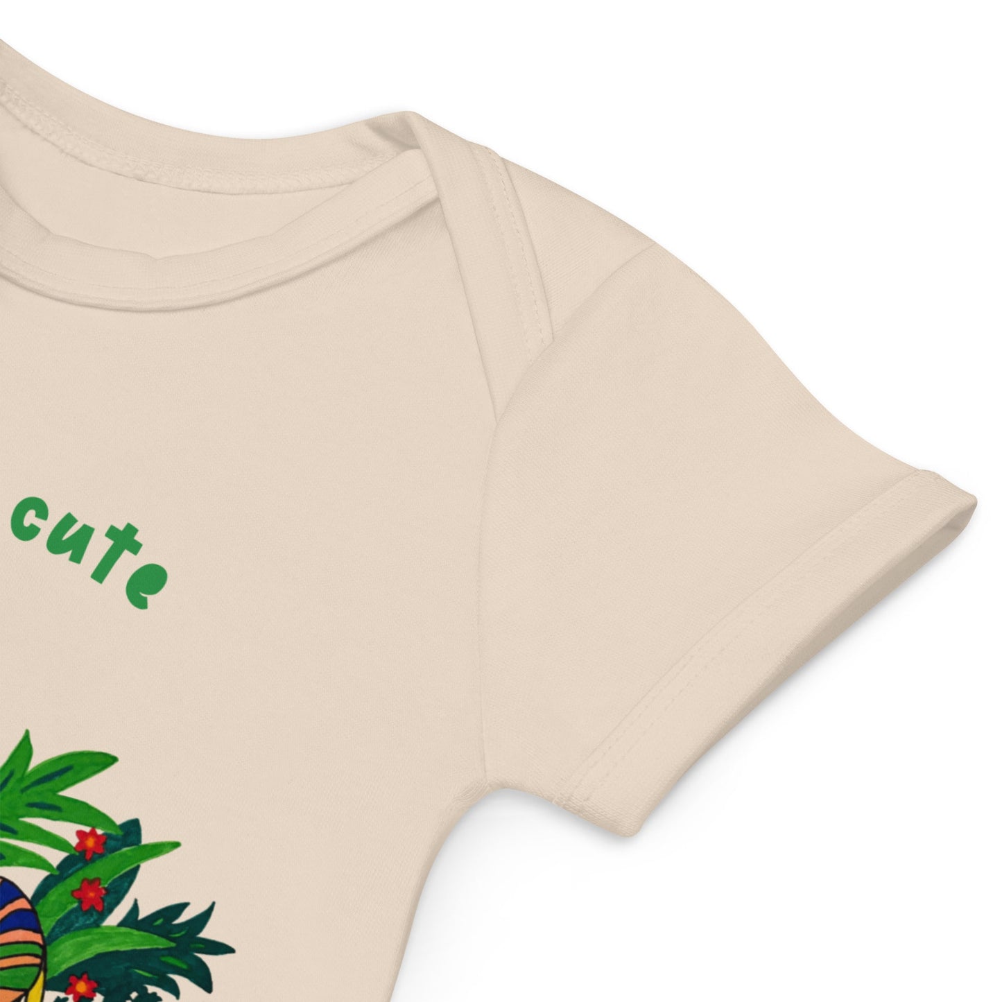 Sleeve detail of beige baby onesie with green text 'cute' and colorful leaf design on a white background