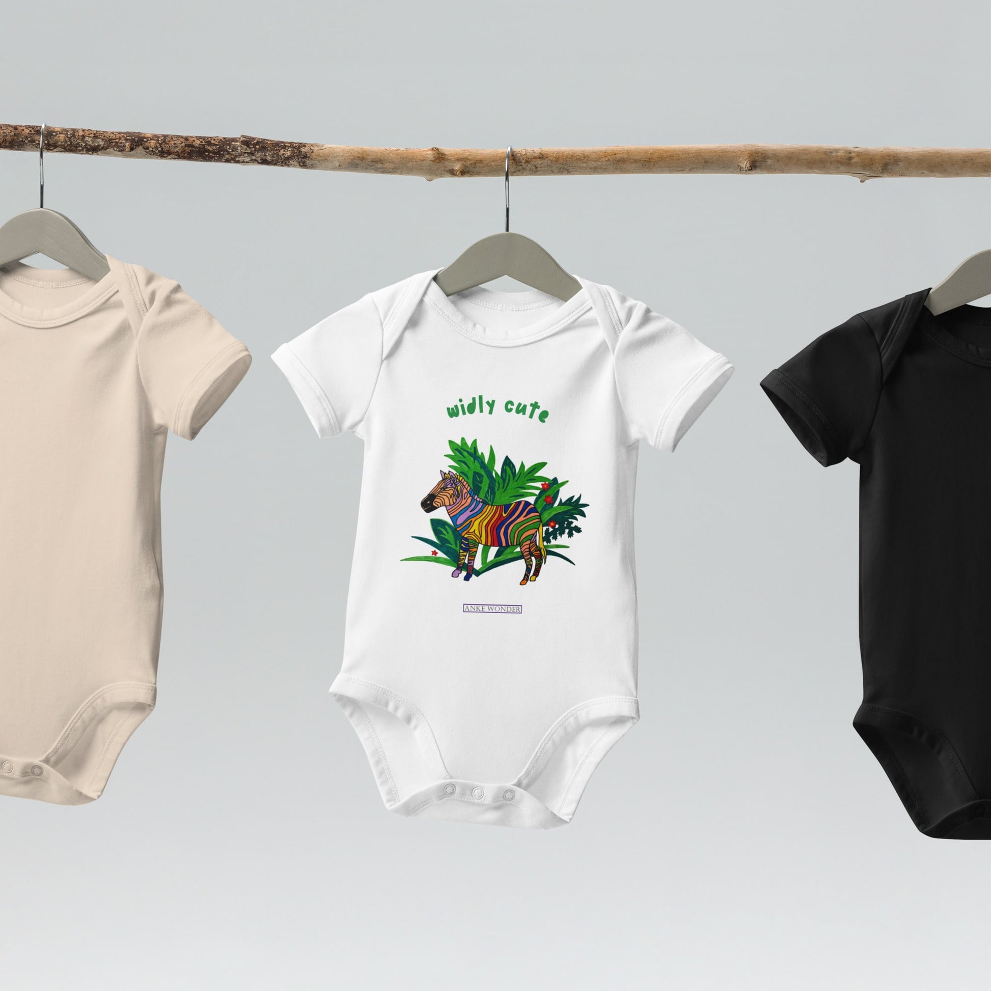 Three baby onesies on hangers with a white baby onesie that has a colorful zebra design on a white background