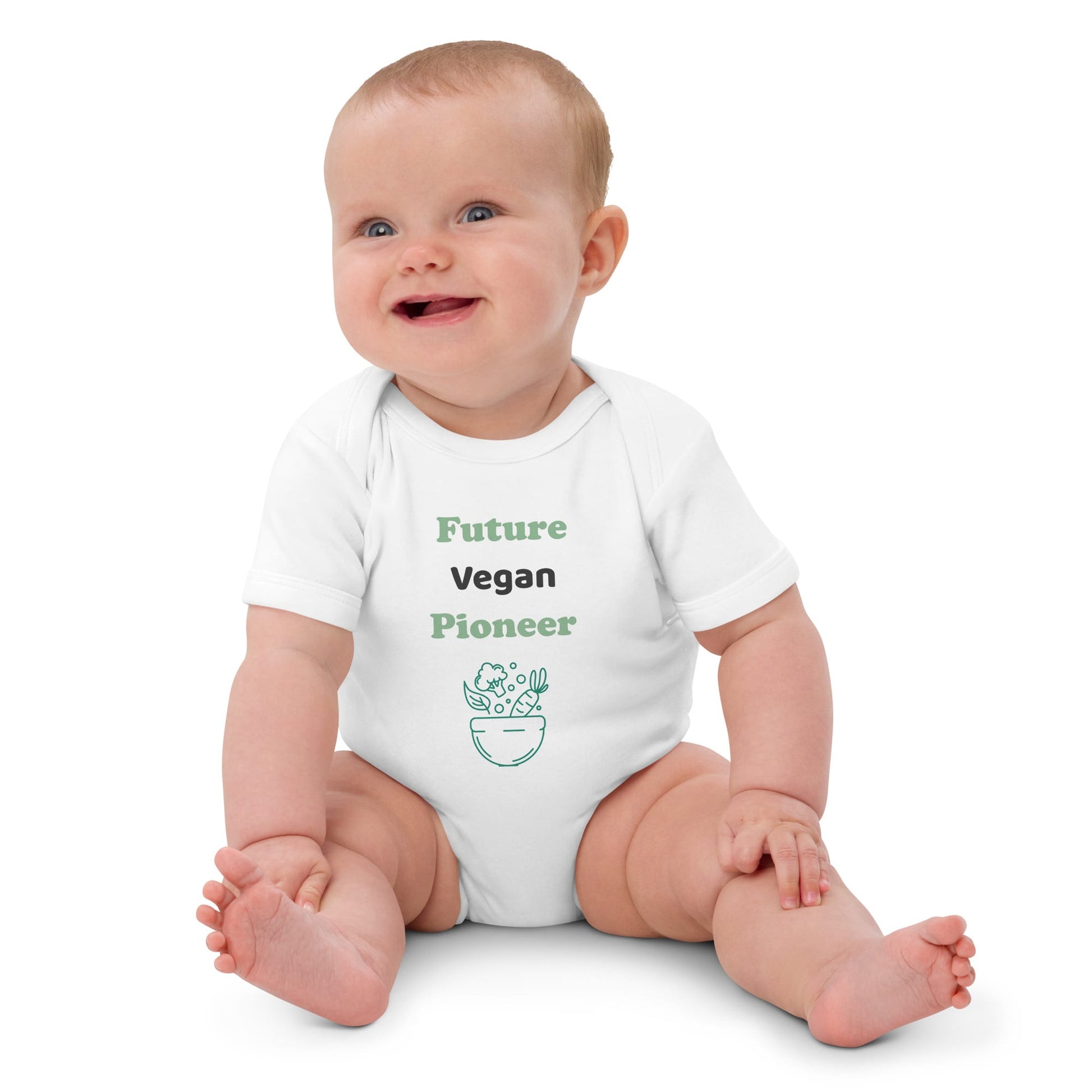  A baby girl sitting and wearing a white organic cotton bodysuit with “Future Vegan Pioneer” printed in green and black, looking adorable and comfortable.