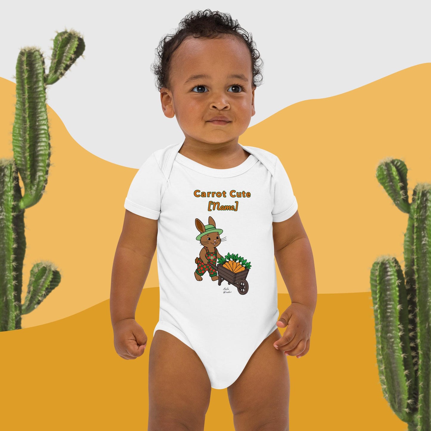 Child wearing a white onesie with a cartoon bunny and carrot cute text, standing against a desert landscape with cacti.