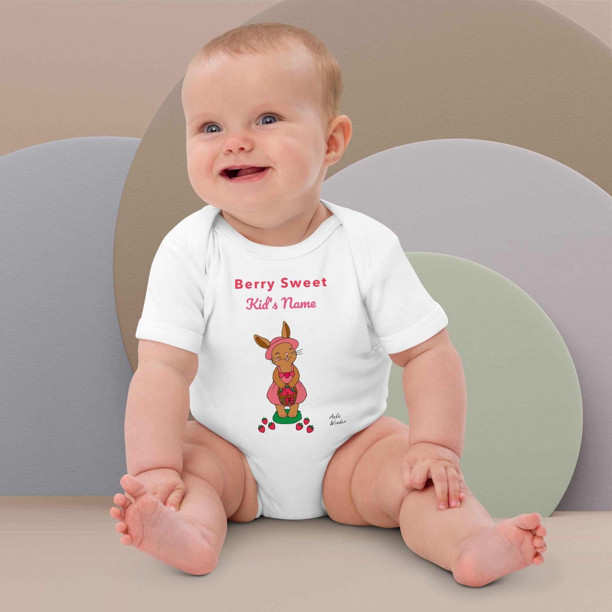 Baby Girl wearing a white onesie printed bunny with strawberries design and text 'Berry Sweet Name', sitting on a plain background.