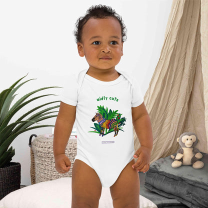 Baby boy wearing a white onesie with a zebra design and the words 'widly cute' by Anke Wonder.