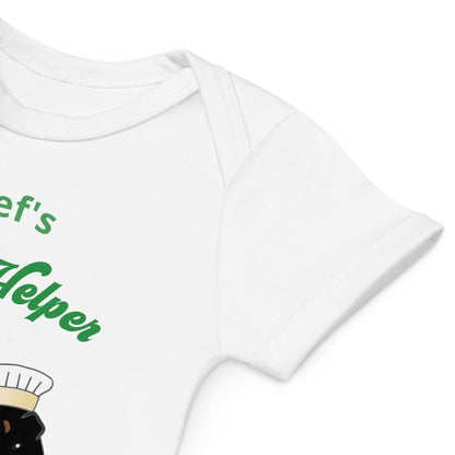 White organic cotton baby bodysuit sleeve close-up with partial guinea pig design and green text, showcasing fabric texture.