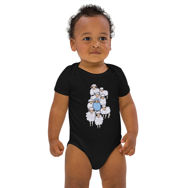 Black baby boy standing, wearing a black organic cotton bodysuit featuring a playful blue sheep design among a sheep flock - designed by Anke Wonder.