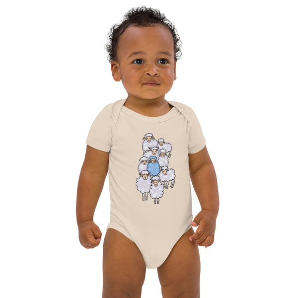 Black baby boy standing, wearing a natural organic cotton bodysuit featuring a playful blue sheep design among a sheep flock - designed by Anke Wonder.