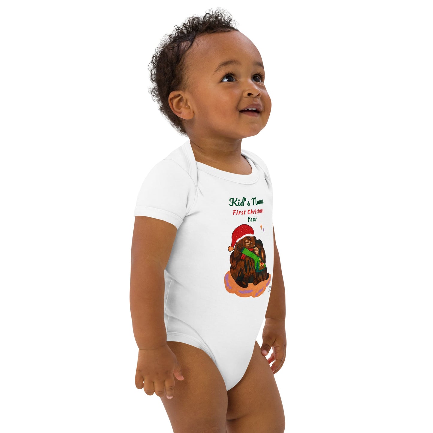 Side view of baby boy wearing a white onesie with a Christmas design on a white background