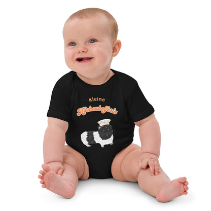 Organic baby bodysuit in black with a guinea pig chef illustration and the German "Kleine Küchenhelferin" text.