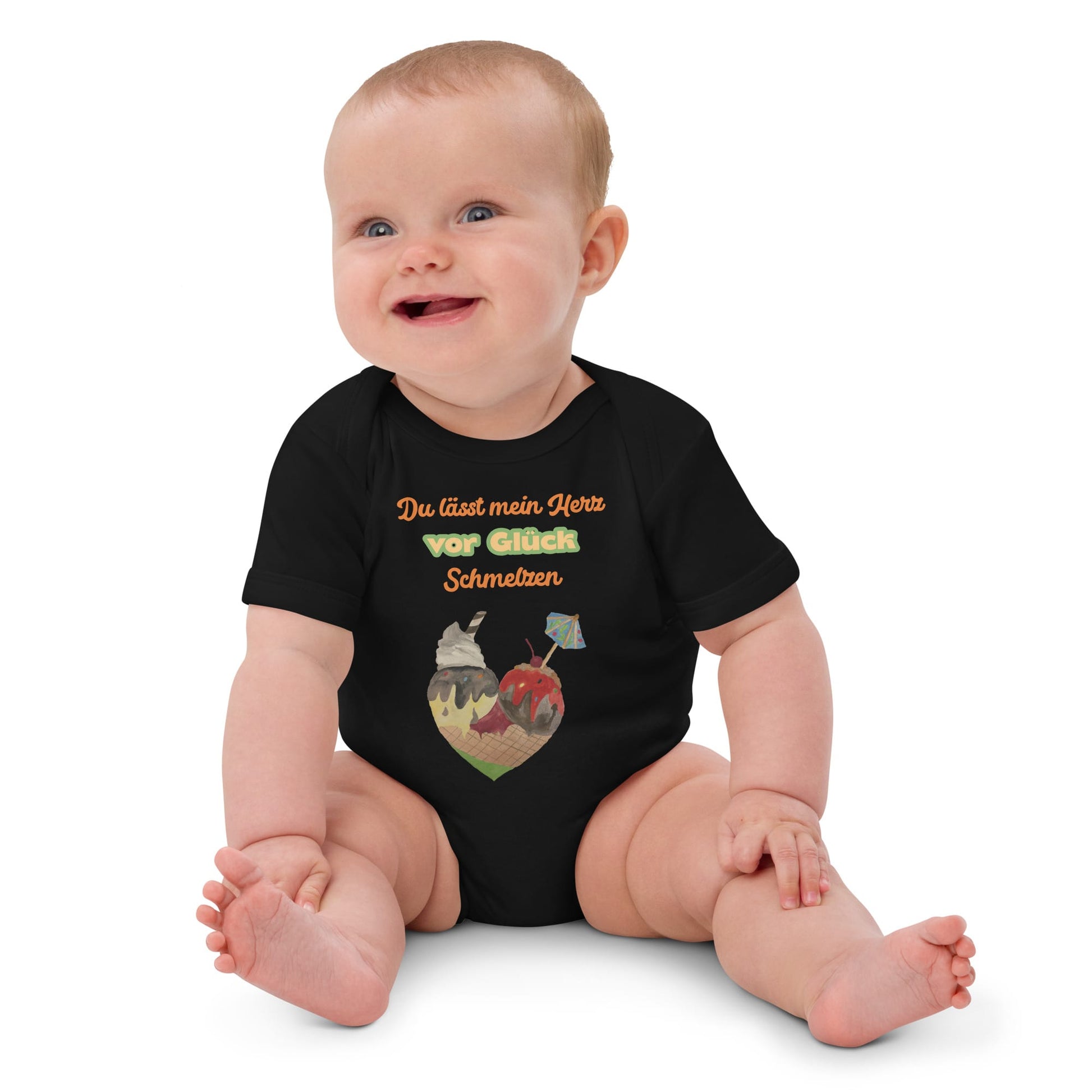 Smiling baby girl wearing black organic bodysuit with colorful German quote and ice cream cone heart.