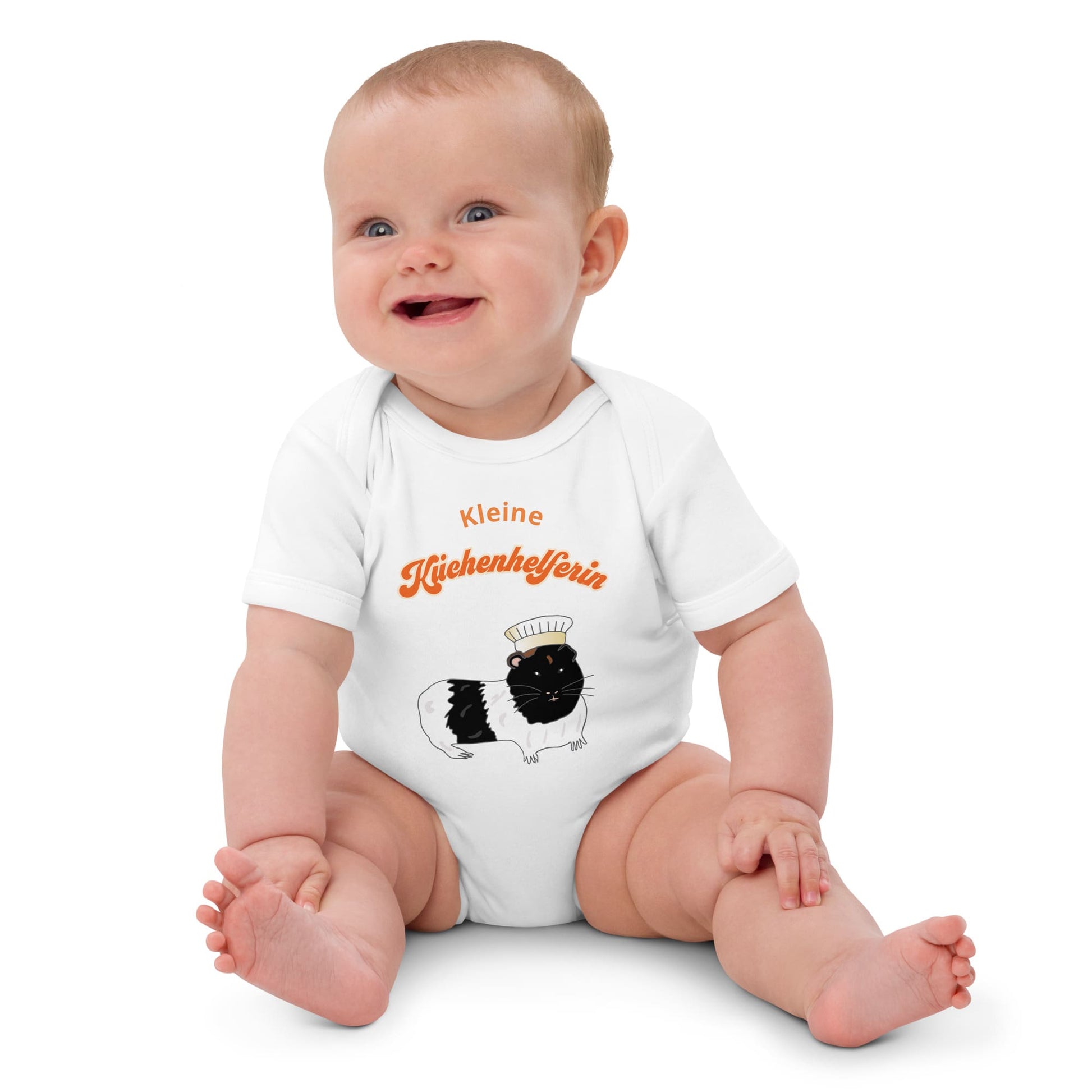White organic baby bodysuit featuring a hand-painted guinea pig in a chef’s hat with playful German  text.