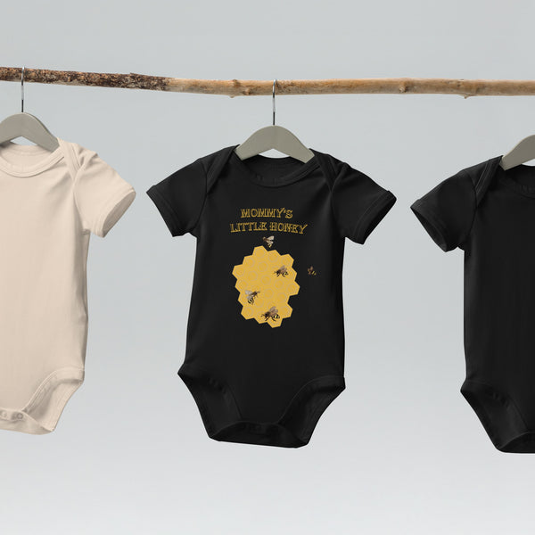 Black organic cotton baby bodysuit with a honeycomb and bee design, featuring "Mommy’s Little Honey" text, displayed on a hanger.