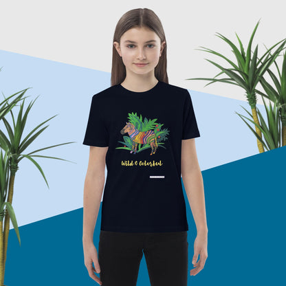 Girl wearing a navy t-shirt with a colorful zebra design and text, standing against a blue and white background with plants.