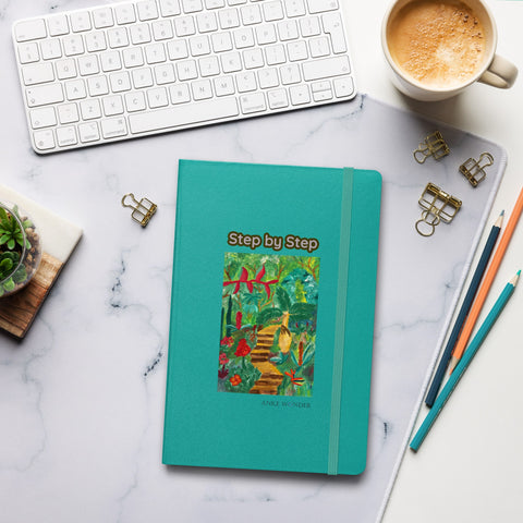 Teal notebook titled 'Step by Step' and a Tropical Artwork on a marble desk with office supplies and a cup of coffee.