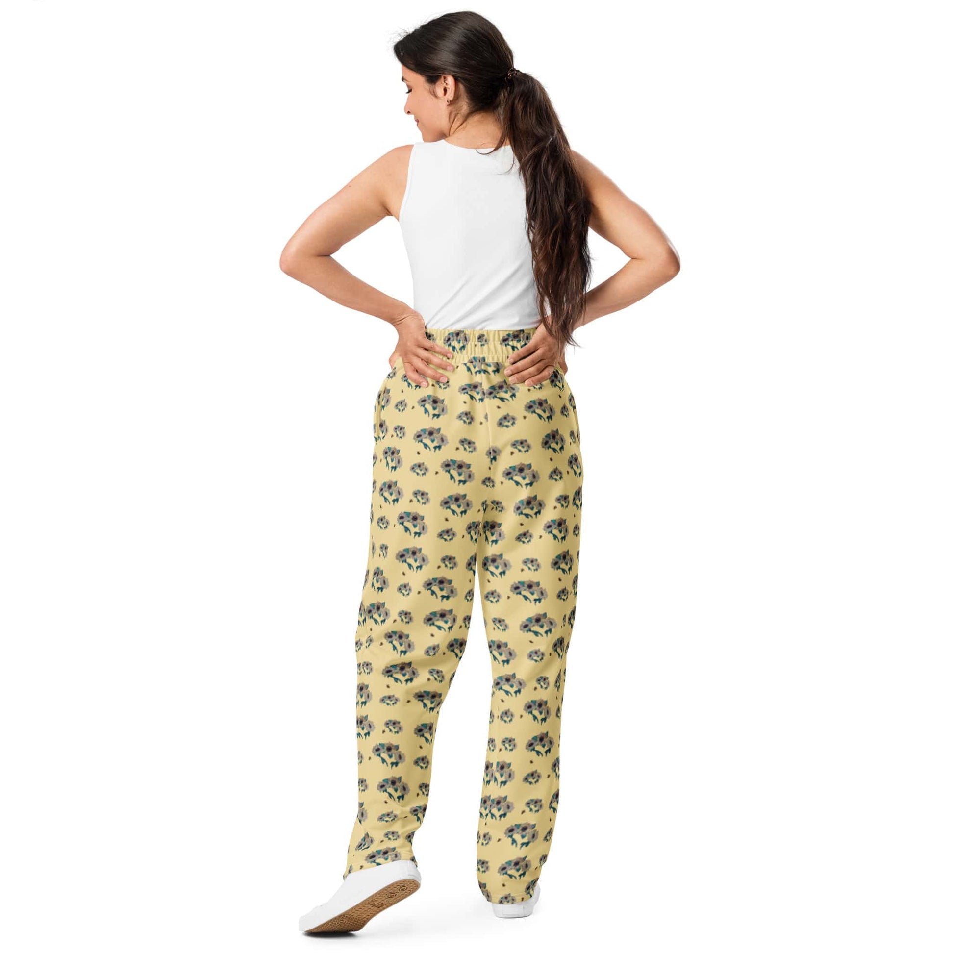 Backside of woman wearing yellow floral pants on a white background