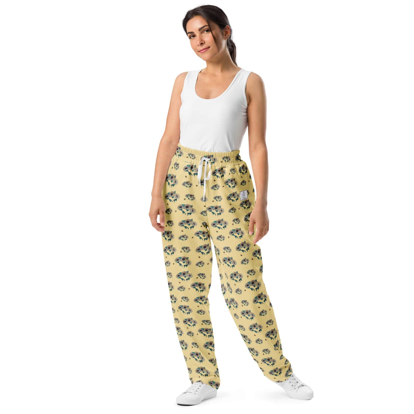 Woman wearing yellow sunflower pants and a white top on a white background