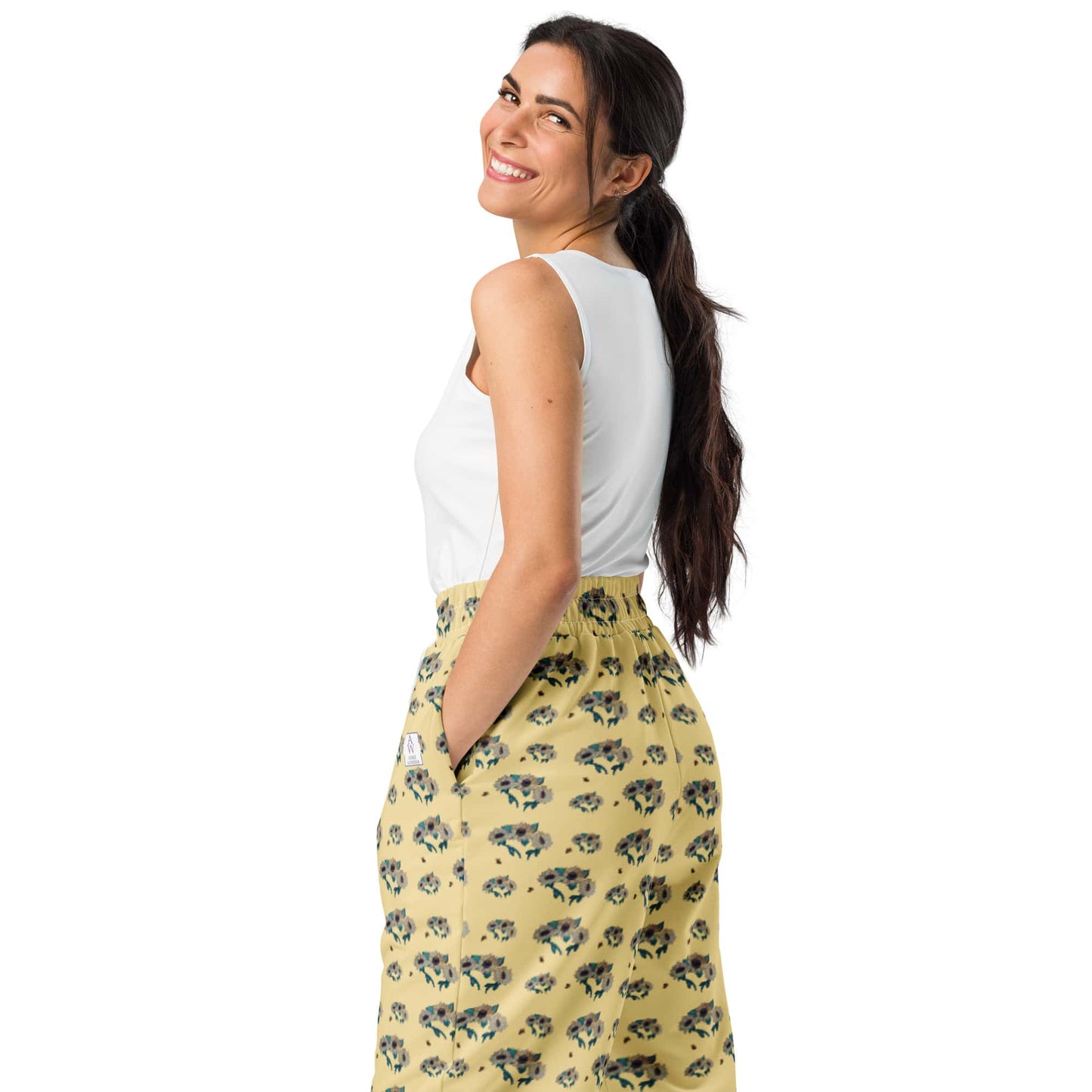 Woman wearing a white top and yellow floral pants on a white background